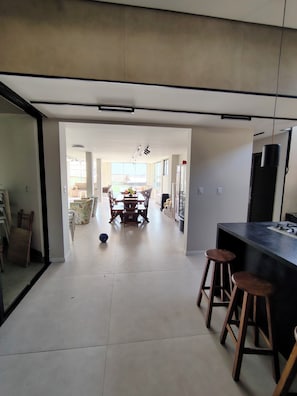 Una cocina moderna con una isla central, taburetes de bar y un comedor con sillas y una mesa.