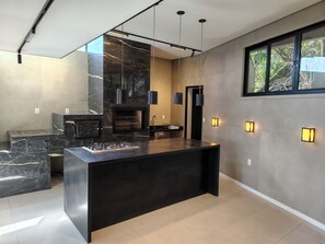 A modern kitchen with a marble countertop, built-in stove, and pendant lighting.
