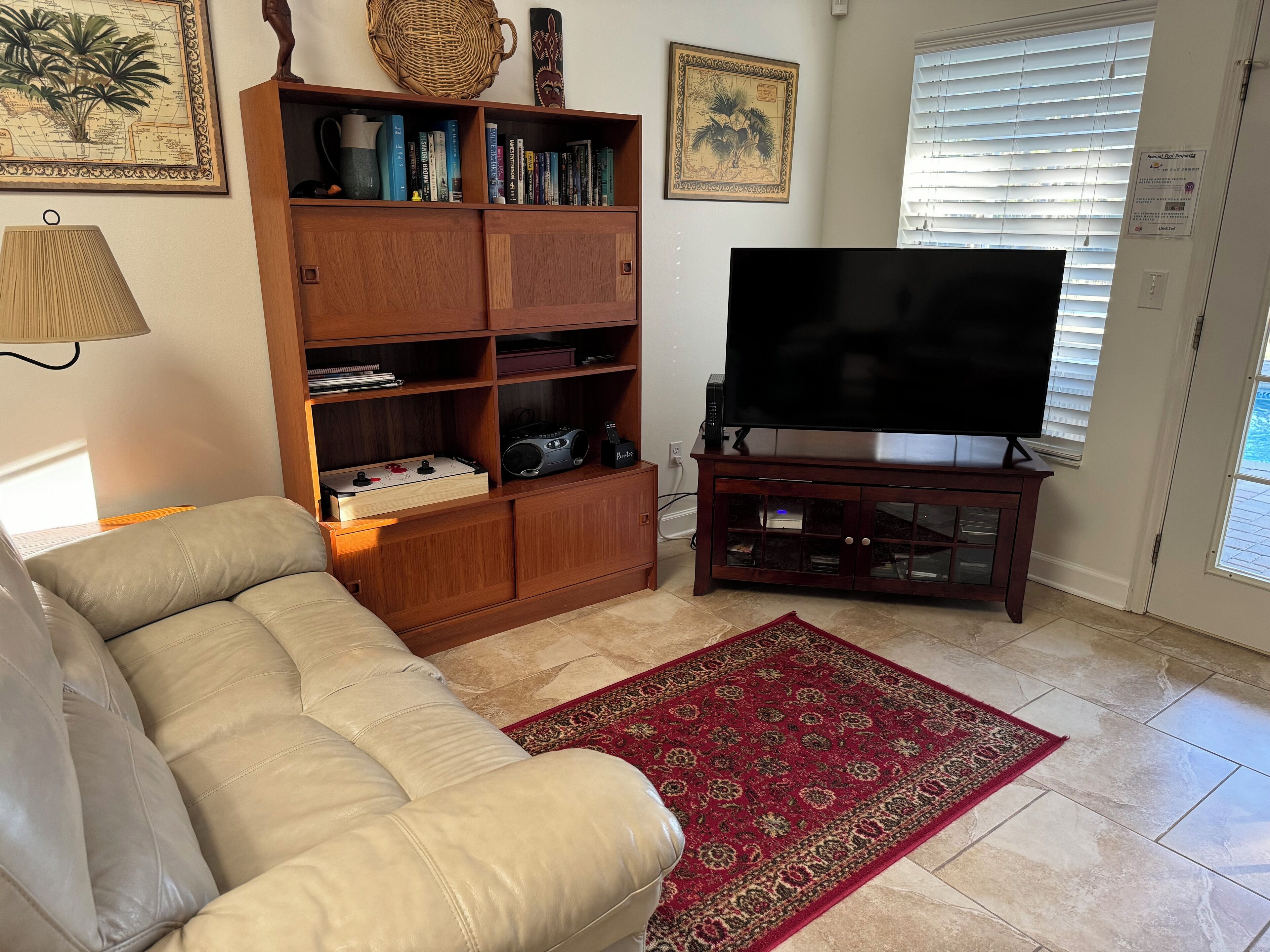 Ein Wohnzimmer mit beiger Couch, Holz-Unterhaltungseinrichtung und einem großen Flachbildfernseher.