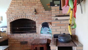 Une cuisine aux murs en briques, dotée d’un four encastré, d’une table en bois et d’une cuisinière à gaz.
