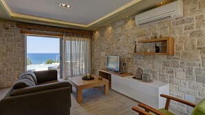 Un salon avec un mur en pierre, un téléviseur, une table basse en bois et un canapé.