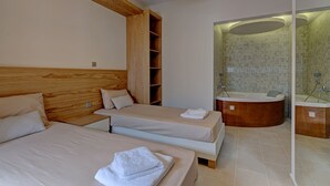 Une chambre d’hôtel avec deux lits, une tête de lit en bois, une étagère intégrée et une salle de bain dotée d’une baignoire et de murs carrelés.