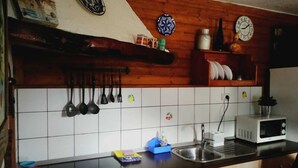 A kitchen with wooden cabinets, a black countertop, a sink, a microwave, and various kitchen utensils hanging on the wall. - Nice country house with terrace, sea and mountains views (Tigaday)