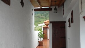 A corridor with a wooden ceiling, white walls, and a view of a hillside. - Nice country house with terrace, sea and mountains views (Tigaday)