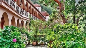 A traditional building with arched balconies and a garden area with various plants and a pink flower. - Mountain and Private Beach VILLA EAGLE  2-10 pers. (Chavgas)