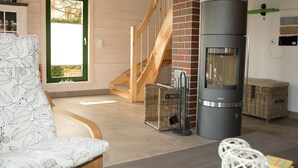 Una sala de estar acogedora con un sofá, una chimenea, cestas de mimbre y una escalera.