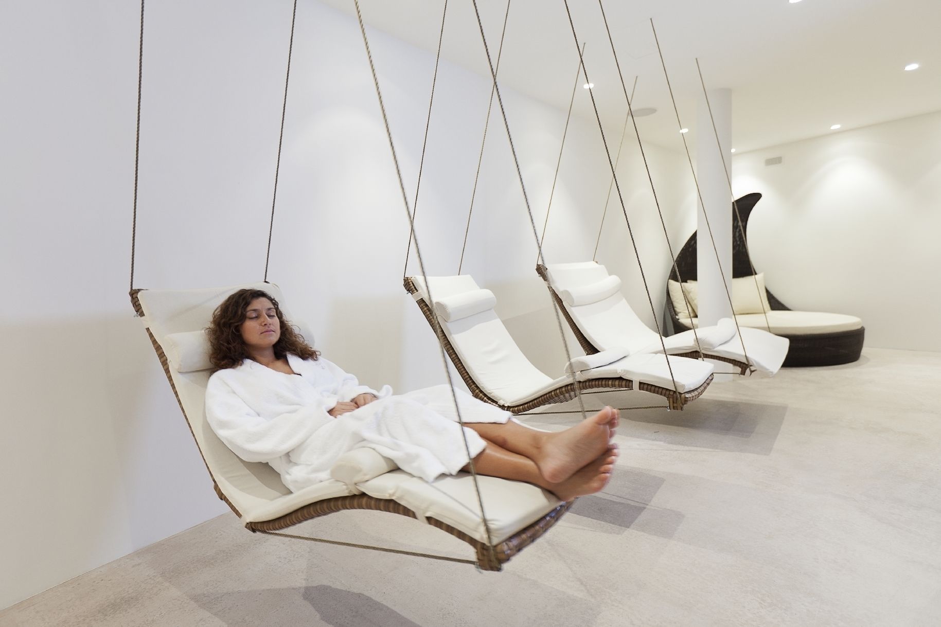 A spa room with hanging chairs and a lounge area.