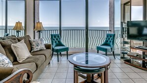 A spacious living area with a large window overlooking the sea, furnished with a sofa, chairs, and a coffee table. - Rare Two-Story Oceanfront Penthouse • 5 Balconies • Stunning Beach Views (Myrtle Beach)
