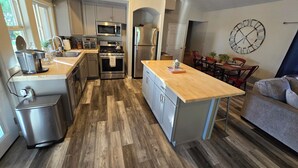 A modern kitchen with stainless steel appliances, a wooden island, and a dining area with a clock on the wall. - Private Guest House, Sleeps 6, Infinity Pool, Jacuzzi, Pet-Friendly, Wineries (Paso Robles)