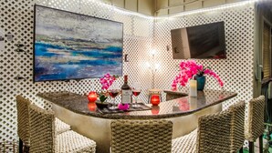 A bar area with a round table, wicker chairs, a large abstract painting, and decorative flowers. - Hidden Gem! Vista 4B, Private, Outdoor Living, Spacious, Work Crews & Families (Vista)