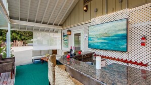 A covered outdoor seating area with wicker furniture, a granite bar, and a large TV screen. - Hidden Gem! Vista 4B, Private, Outdoor Living, Spacious, Work Crews & Families (Vista)