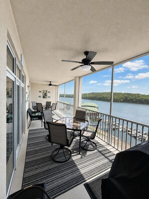 A balcony with a table and chairs, a ceiling fan, and a view of a lake.