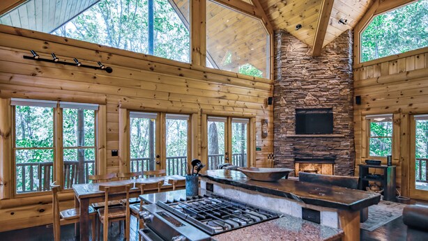 A spacious lodge with a stone fireplace, wooden dining area, and large windows offering views of the forest. - Blue Ridge Mountain Serenity at The Summit: Hot Tub, Tubing & Hiking Trails (Blue Ridge)