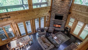A spacious living area with a stone fireplace, wooden furniture, and large windows offering views of the outdoors. - Blue Ridge Mountain Serenity at The Summit: Hot Tub, Tubing & Hiking Trails (Blue Ridge)