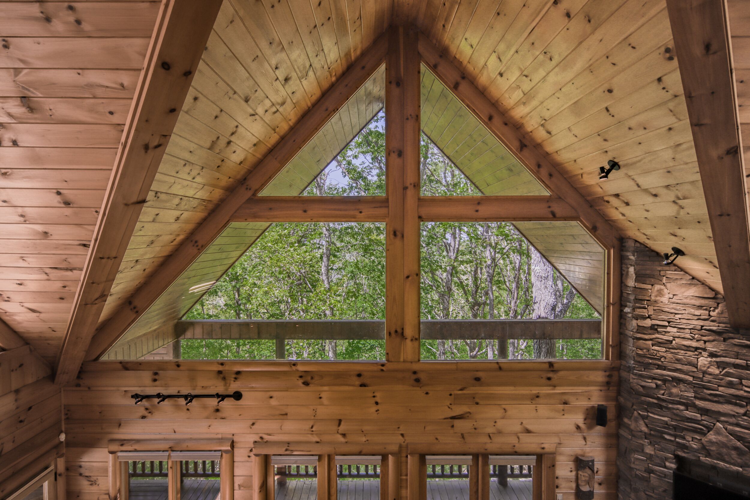 A wooden cabin with a triangular roof, stone wall, and multiple windows.