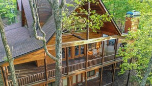 A multi-level wooden cabin with a balcony and a deck, surrounded by trees. - Blue Ridge Mountain Serenity at The Summit: Hot Tub, Tubing & Hiking Trails (Blue Ridge)