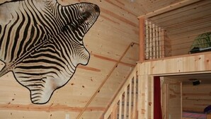 A wooden interior with a zebra head mural, a lofted sleeping area, and a visible staircase. - The Bunkalow Lakefront Compound w Lifts for your Speed Boat & Tritoon (Ludington)