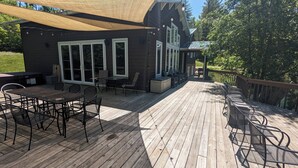 A wooden deck with outdoor furniture, a covered seating area, and a house with large windows. - Secluded Waterfront Home Located On 82 Private Acres! Close to HH State Park!
 (Laurelville)