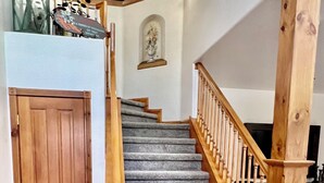 A wooden staircase with a handrail, leading to a landing with a door and a small decorative shelf.