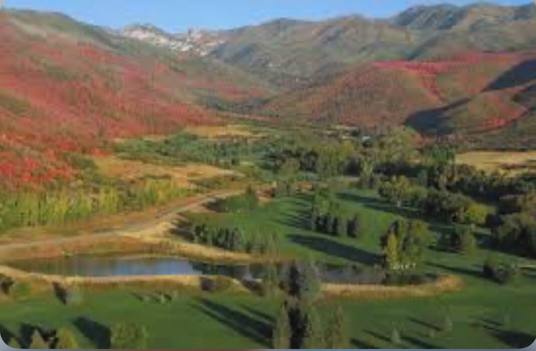 A mountainous landscape with a river and fields.