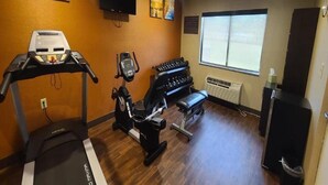 A gym with a treadmill, stationary bike, and weight bench.