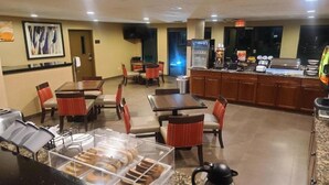 A hotel lobby with seating areas, a counter with a coffee machine, and a trash bin.