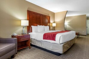 A hotel room with a large bed, two bedside tables, a desk, a chair, and a lamp. - Comfort Inn and Suites (Alvarado)