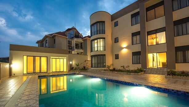 A modern hotel with a swimming pool, multiple balconies, and well-lit windows.