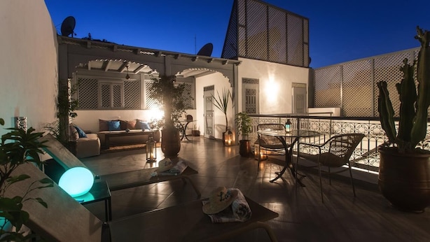 An outdoor patio area with seating, a table, and potted plants. - Riad L'Arganier (Marrakech)