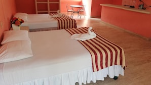 Une chambre d’hôtel avec deux lits, une petite table, des chaises et un téléviseur.
