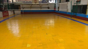 Un terrain de volleyball intérieur avec un sol jaune et des murs bleus et rouges.