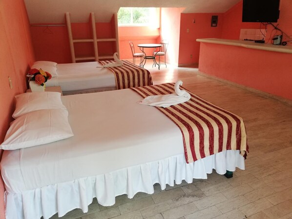 A hotel room with two beds, a small table, and a chair.