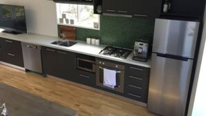 Une cuisine moderne avec des meubles de couleur sombre, un réfrigérateur en acier inoxydable, une cuisinière à gaz et un lave-vaisselle.