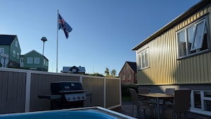 A backyard with a swimming pool, a barbecue grill, and a dining area with outdoor furniture. - Restored house in Stykkishòlmur old town (Stykkishólmur)