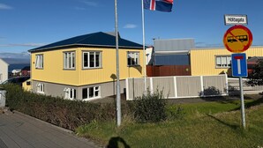 A yellow building with a flagpole, a no bus stop sign, and a street lamp. - Restored house in Stykkishòlmur old town (Stykkishólmur)