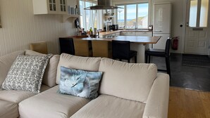 A modern kitchen with white cabinetry, a central island, and a view of the outdoors. - Restored house in Stykkishòlmur old town (Stykkishólmur)