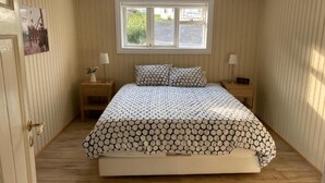 A bedroom with a bed, two bedside tables, a window, and a door. - Restored house in Stykkishòlmur old town (Stykkishólmur)