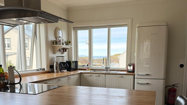 A kitchen with a wooden island, black chairs, a white refrigerator, and a window with a view of the outside. - Restored house in Stykkishòlmur old town (Stykkishólmur)