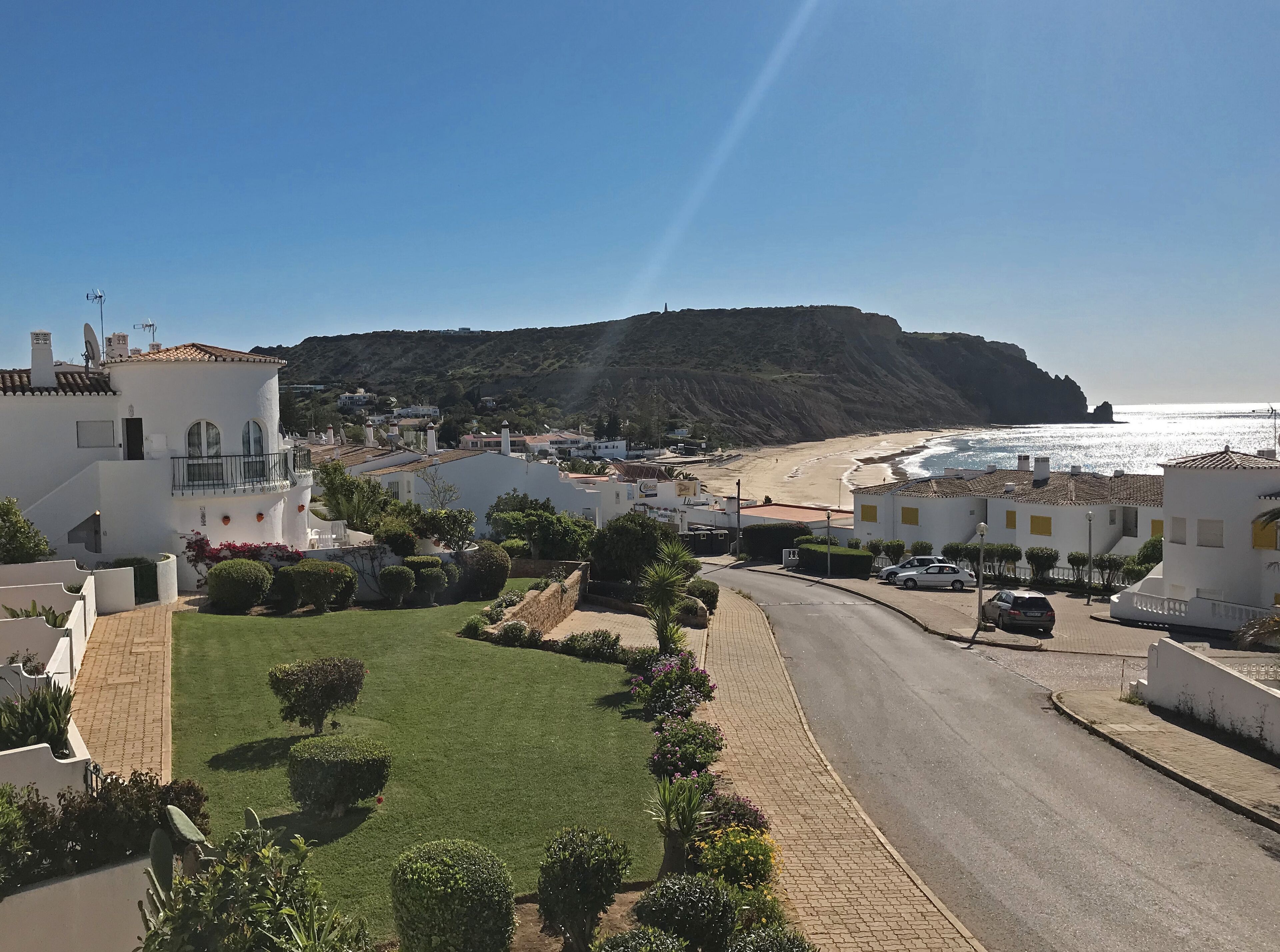 Una località costiera con edifici bianchi, una spiaggia e una collina sullo sfondo.