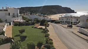 A coastal town with white buildings, a beach, and a hill in the background. - Cozy Apartment with Stunning Sea Views, One Minute Walk from the Beach (Praia da Luz, Lagos)