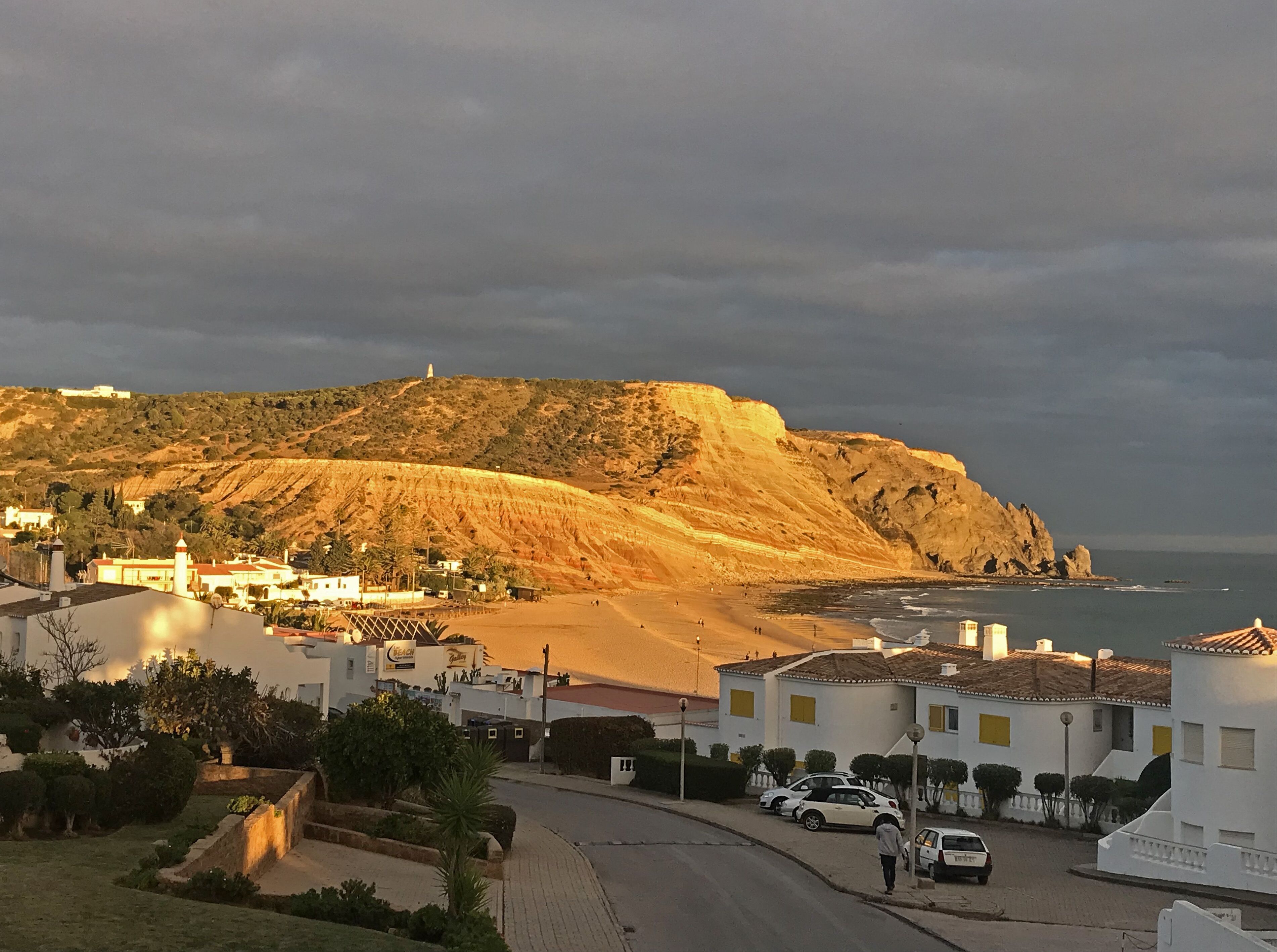 A coastal town with a prominent hill, a beach, and a lighthouse.