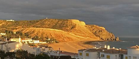 A coastal town with a prominent hill, a beach, and a lighthouse.