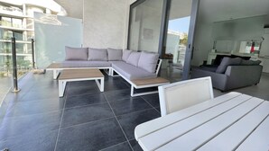 Un espacio al aire libre moderno con un sofá modular, una mesa de madera y un banco blanco.