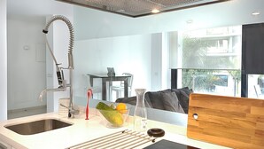 Una cocina moderna con un lavamanos de acero inoxidable, horno empotrado y tabla de cortar de madera sobre la encimera.