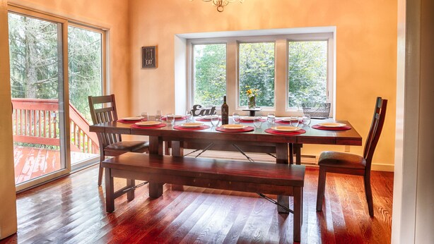 A dining area with a wooden table set for four, large windows, and a chandelier. - Country Escape! 5 bed/5bath, 2 acre pond, pool/Foosball tables, Fire pit, Sauna (Roxbury)