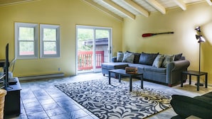 A living room with a gray sofa, a patterned rug, and a remote control on a coffee table. - Country Escape! 5 bed/5bath, 2 acre pond, pool/Foosball tables, Fire pit, Sauna (Roxbury)