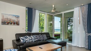 Ein modernes Wohnzimmer mit einer schwarzen Ledersofa, gemusterten Kissen, einem Holztisch und einem Stadtbild.