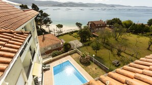 A residential building with a swimming pool, a beach, and a view of the sea.