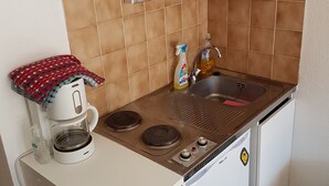 Et lille tekøkken med kaffemaskine, vask og en mindre komfur.