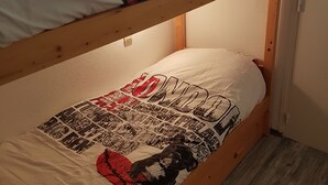 En køjeseng med en overkøje med et mønstret tæppe og en underkøje med et grafisk print.